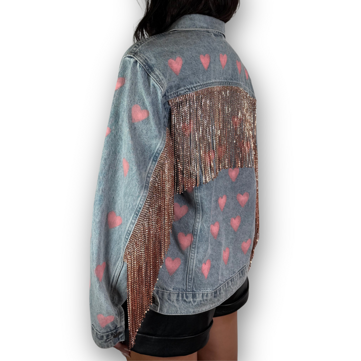 Denim jacket with heart patterns and fringe details on a white background